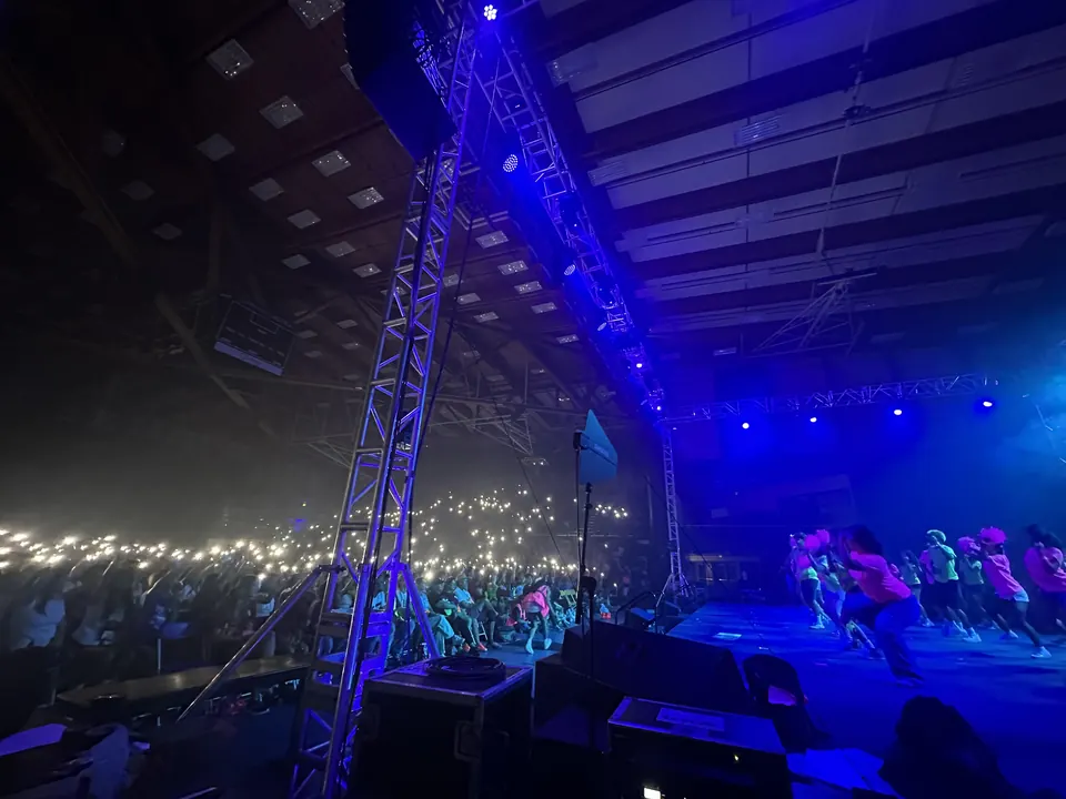 Wide stage view of the Orange County Leadership Conference at the UCSB Events Center with the audience illuminated by phone lights